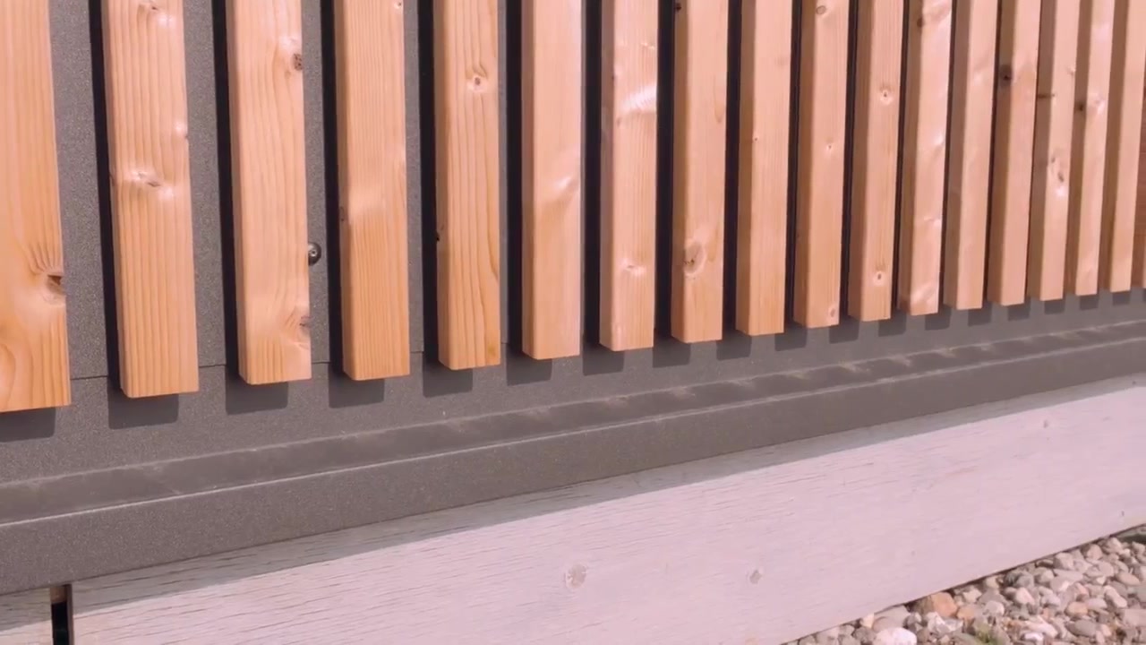 Base of an Aluwood slat facade where the slats end above a dark grey base flashing